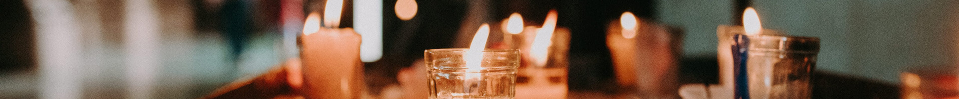 Verschiedenartige Kerzen brennen auf einem Tisch.