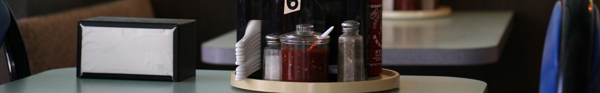 Gewürze und Servietten in Haltern stehen auf einem Restaurant-Tisch.