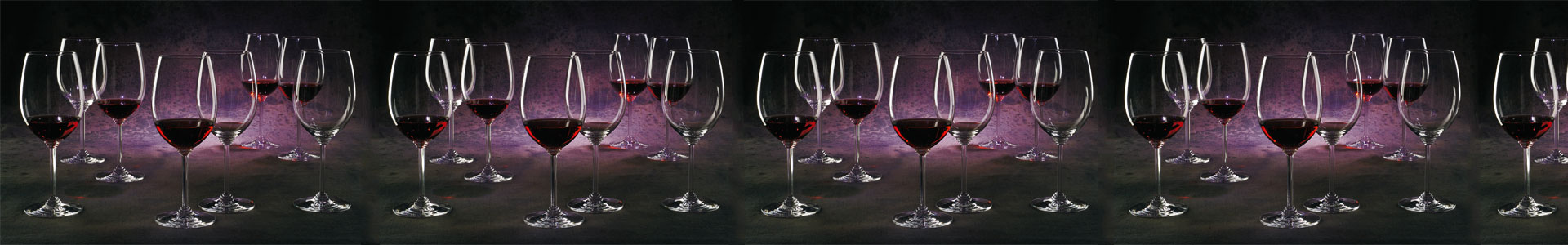 Zahlreiche Weingläser aus der Serie Riedel Wine sind mit Rotwein gefüllt und stehen in violettem Licht.