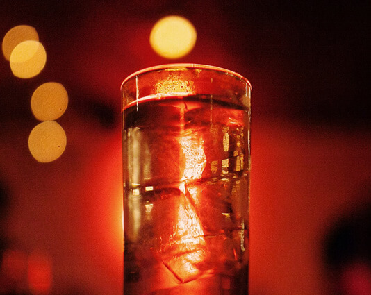Gefülltes Schnapsglas in rot-goldenem Licht.