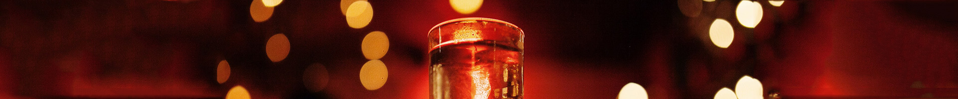 Gefülltes Schnapsglas in rot-goldenem Licht.