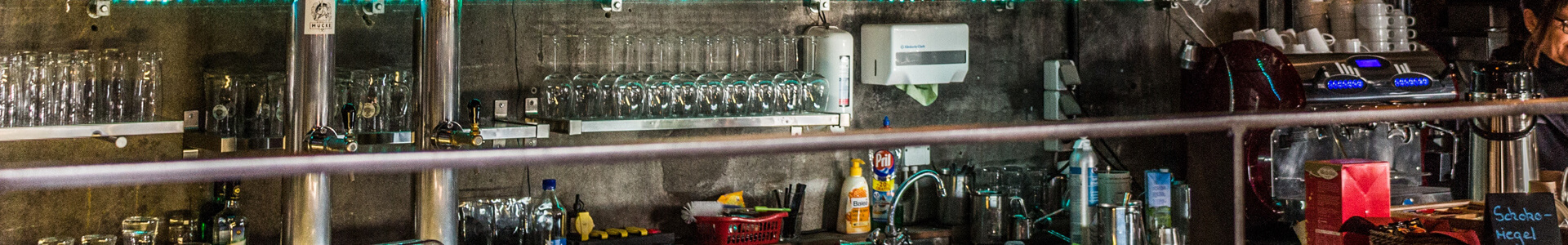 Gläser, Spülbecken und Geschirr hinter dem Tresen einer Bar.