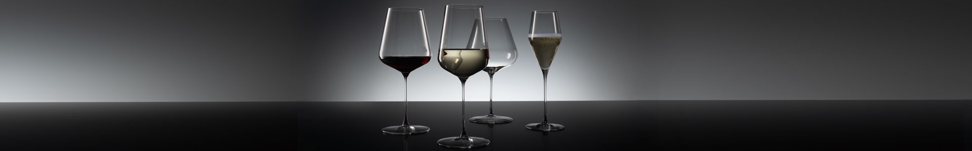 Weingläser von Spiegelau stehen auf einer dunklen Fläche.