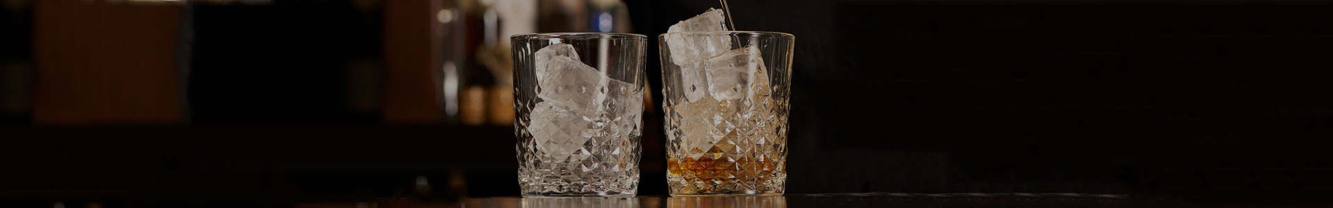 Zwei Tumbler Gläser mit Dekor der Carats-Serie von Onis stehen auf einem Bar-Tresen.